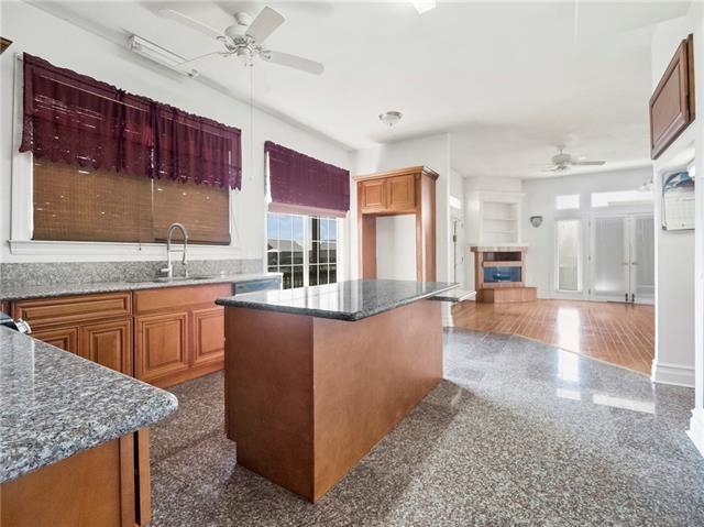 30 Clinton Dr, New Orleans, LA 70129 - kitchen with a ceiling fan, healthy amount of natural light, a tile fireplace, and brown cabinets