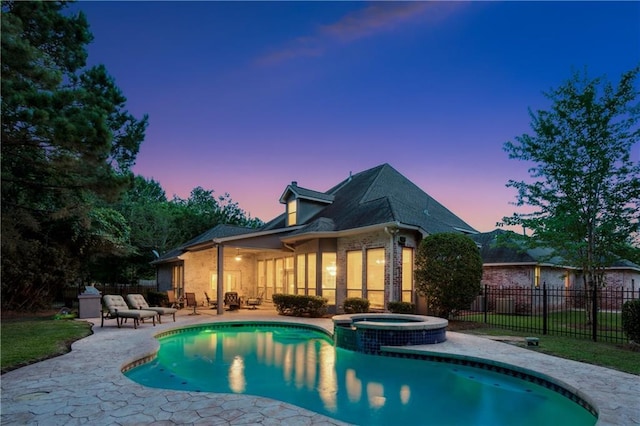 356 Aspen Ln, Covington, LA 70433 - back of house at dusk featuring a patio area, a pool with connected hot tub, and brick siding