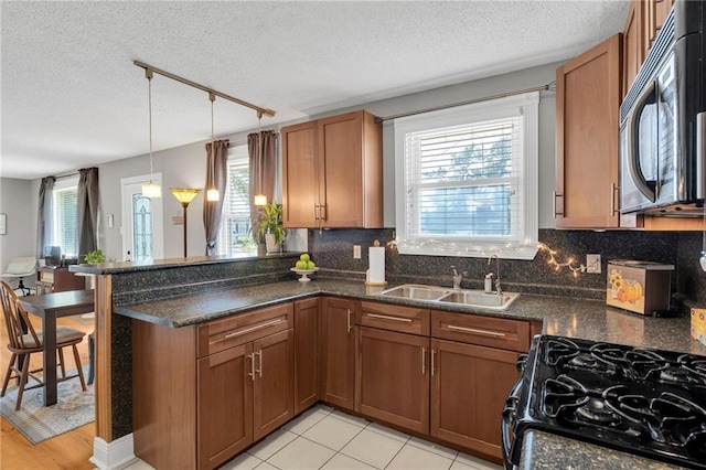 301 Rural St, River Ridge, LA 70123 - kitchen featuring black microwave, rail lighting, a textured ceiling, a peninsula, and plenty of natural light