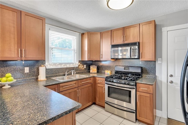 301 Rural St, River Ridge, LA 70123 - kitchen with stainless steel appliances, dark countertops, a textured ceiling, decorative backsplash, and light tile patterned flooring