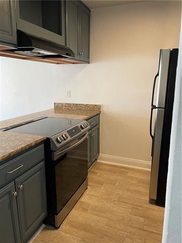 3805 Houma Blvd Unit B304, Metairie, LA 70006 - kitchen featuring electric range, freestanding refrigerator, light wood finished floors, and dark stone counters