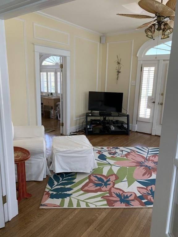 2527 Calhoun St, New Orleans, LA 70118 - living area featuring ceiling fan, wood finished floors, ornamental molding, and a decorative wall