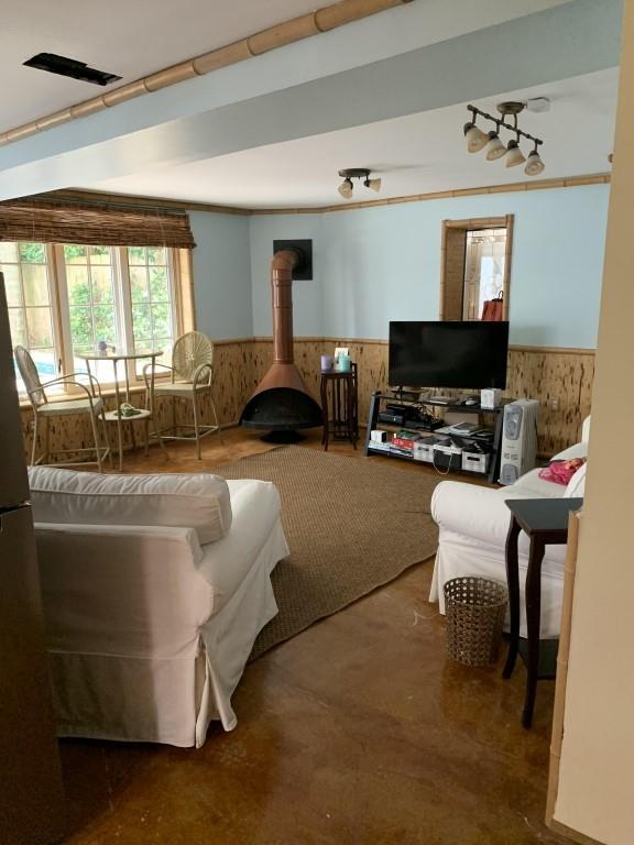 2527 Calhoun St, New Orleans, LA 70118 - living area featuring a wainscoted wall, a wood stove, and wood walls