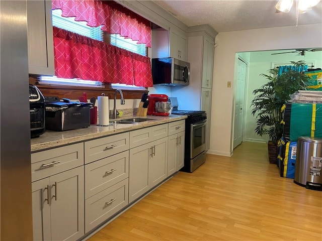 8007 Drum St, New Orleans, LA 70126 - kitchen with stainless steel appliances, light wood-type flooring, light stone countertops, a textured ceiling, and gray cabinets