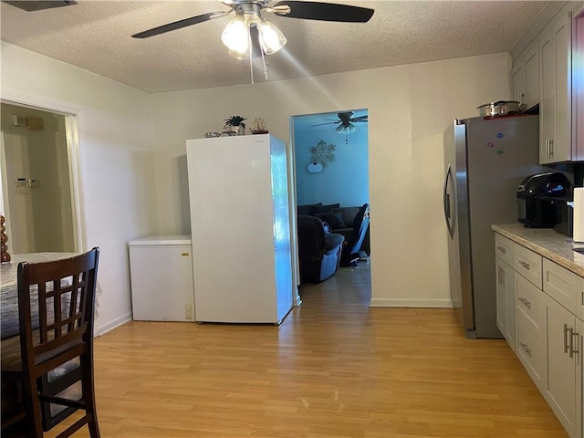 8007 Drum St, New Orleans, LA 70126 - kitchen with ceiling fan, light wood-type flooring, a textured ceiling, refrigerator, and freestanding refrigerator