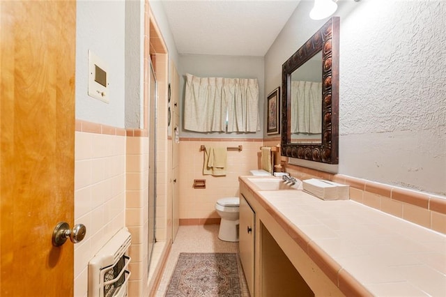 1435 Monterrey Blvd, Baton Rouge, LA 70815 - bathroom featuring tile walls, a shower stall, vanity, wainscoting, and a textured ceiling