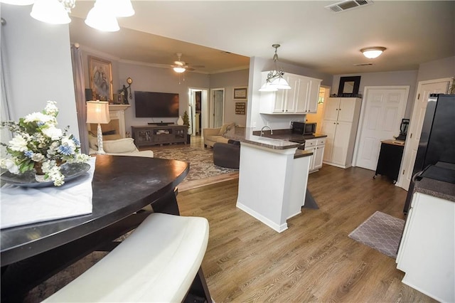 43126 Pecan Ridge Dr, Hammond, LA 70403 - kitchen with a peninsula, dark countertops, white cabinets, dark wood-style flooring, and ornamental molding