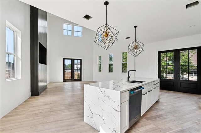 5651 W End Blvd, New Orleans, LA 70124 - kitchen featuring french doors, stainless steel dishwasher, light wood-style floors, hanging light fixtures, and a towering ceiling