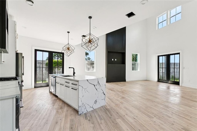 5651 W End Blvd, New Orleans, LA 70124 - kitchen with plenty of natural light, light wood-style flooring, white cabinets, a chandelier, and a towering ceiling