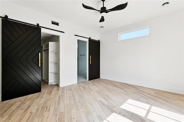 5651 W End Blvd, New Orleans, LA 70124 - unfurnished bedroom with a barn door, light wood finished floors, a spacious closet, a ceiling fan, and a closet