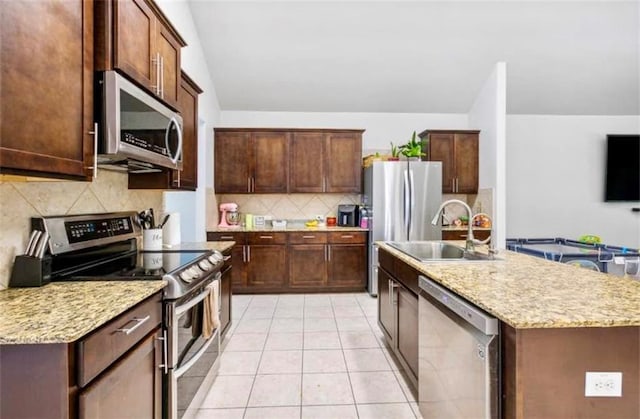 10596 Braves Ave, Denham Springs, LA 70726 - kitchen with stainless steel appliances, tasteful backsplash, an island with sink, light tile patterned flooring, and light stone countertops