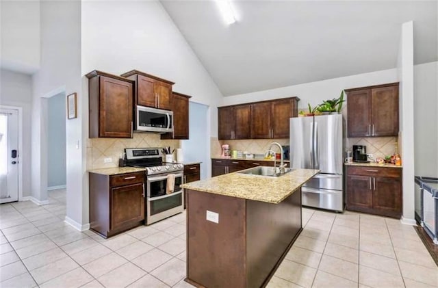 10596 Braves Ave, Denham Springs, LA 70726 - kitchen featuring appliances with stainless steel finishes, tasteful backsplash, light tile patterned floors, and high vaulted ceiling