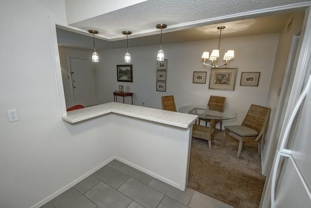 2708 Whitney Pl Unit 901, Metairie, LA 70002 - kitchen with a peninsula, tile patterned flooring, pendant lighting, and a textured ceiling