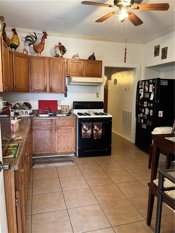 242830 A P Tureaud Ave, New Orleans, LA 70119 - kitchen with range with gas cooktop, under cabinet range hood, freestanding refrigerator, crown molding, and light tile patterned flooring