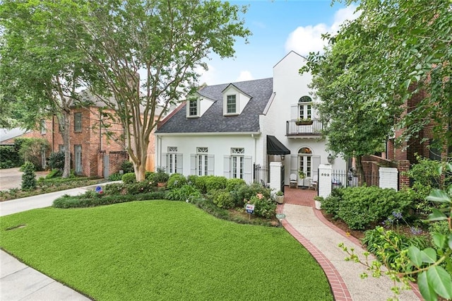 502 Hector Ave, Metairie, LA 70005 - cape cod-style house with french doors, a balcony, stucco siding, a front yard, and roof with shingles
