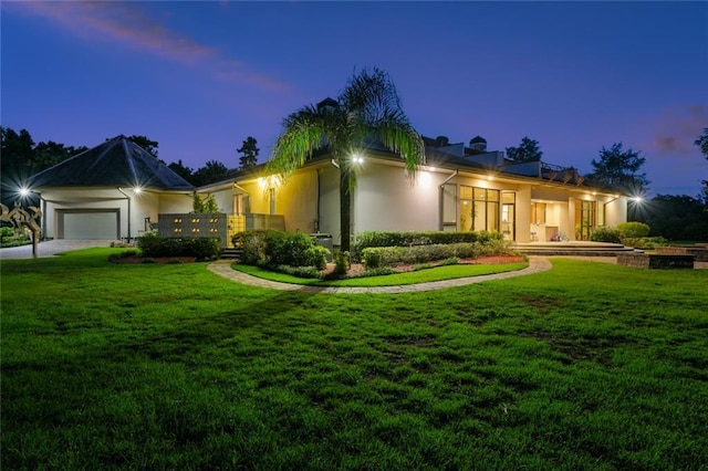 738 English Turn Ln, New Orleans, LA 70131 - view of front of home featuring stucco siding, a garage, and a yard