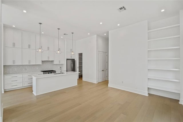 5310 Laurel St, New Orleans, LA 70115 - kitchen with freestanding refrigerator, white cabinets, light wood-style floors, light countertops, and recessed lighting