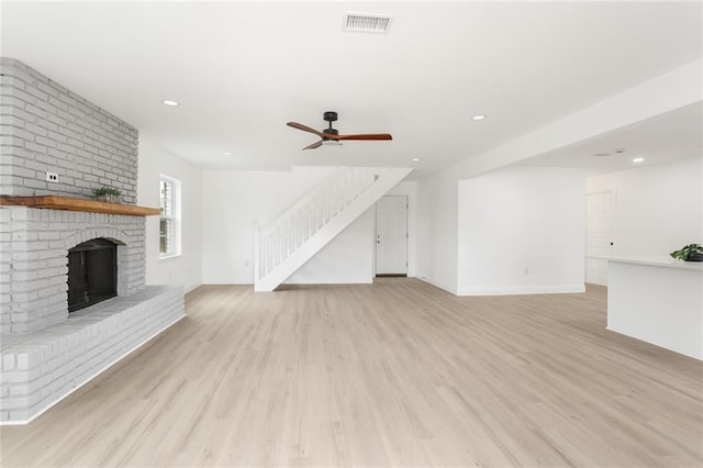 313 Post Dr, Luling, LA 70070 - unfurnished living room with stairs, light wood-style flooring, a ceiling fan, a brick fireplace, and recessed lighting