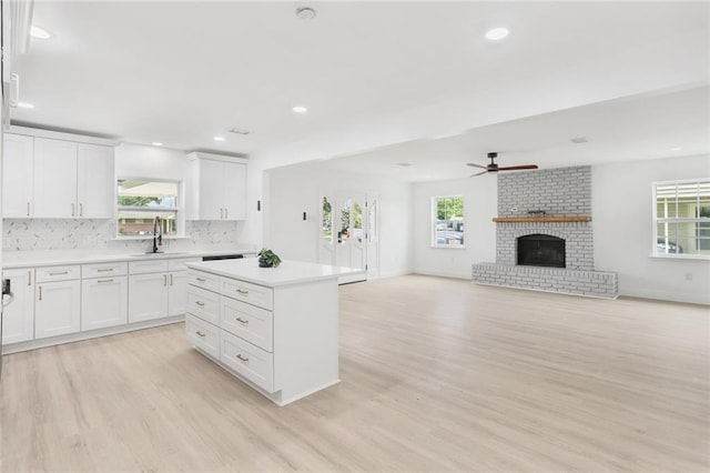 313 Post Dr, Luling, LA 70070 - kitchen with light wood-style floors, ceiling fan, light countertops, a kitchen island, and white cabinets