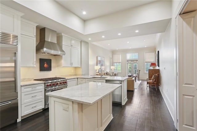 111 Audubon St Unit 202, New Orleans, LA 70118 - kitchen with premium appliances, wall chimney range hood, a peninsula, dark wood-type flooring, and recessed lighting