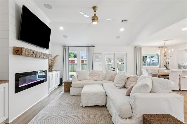 4548 Alphonse Dr, Metairie, LA 70006 - living area with light wood-style floors, a chandelier, a glass covered fireplace, a ceiling fan, and lofted ceiling