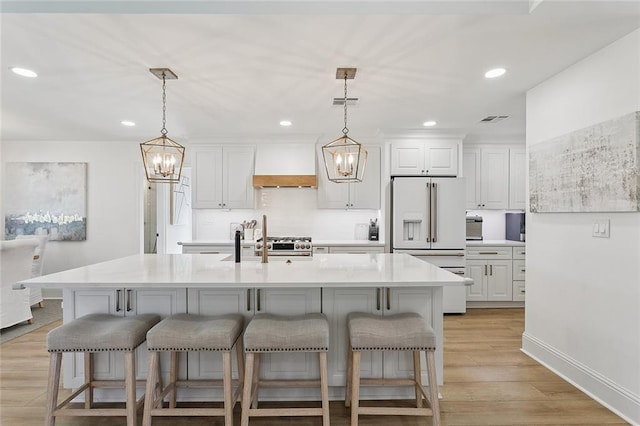 4548 Alphonse Dr, Metairie, LA 70006 - kitchen featuring high end white refrigerator, a chandelier, a breakfast bar area, custom range hood, and recessed lighting