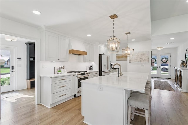 4548 Alphonse Dr, Metairie, LA 70006 - kitchen featuring premium appliances, premium range hood, french doors, light wood-style flooring, and white cabinets
