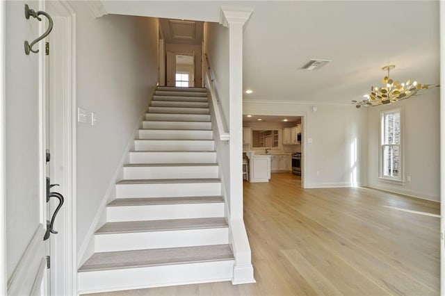 2232 N Starrett Rd, Metairie, LA 70003 - staircase with healthy amount of natural light, wood finished floors, a chandelier, and ornamental molding