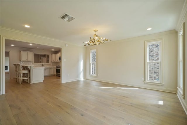 2232 N Starrett Rd, Metairie, LA 70003 - unfurnished living room with a chandelier, crown molding, healthy amount of natural light, light wood finished floors, and recessed lighting