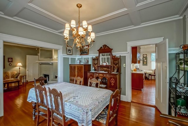 2410 Adams St, New Orleans, LA 70125 - dining space featuring coffered ceiling, wood finished floors, ornamental molding, a chandelier, and a fireplace