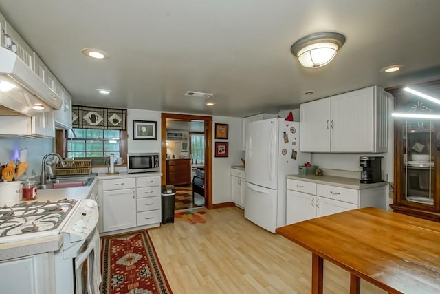 2410 Adams St, New Orleans, LA 70125 - kitchen with white appliances, light wood-style flooring, exhaust hood, white cabinets, and light countertops