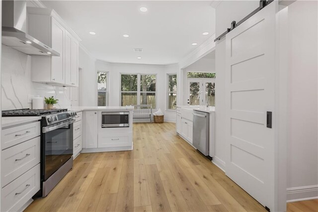 773 Rue Calais, Mandeville, LA 70471 - kitchen with stainless steel appliances, wall chimney exhaust hood, light countertops, a peninsula, and recessed lighting