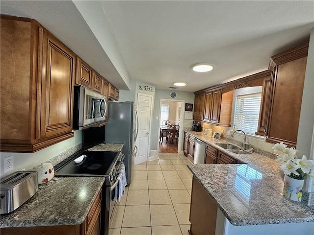 4908 David Dr, Kenner, LA 70065 - kitchen with appliances with stainless steel finishes, dark stone countertops, light tile patterned flooring, a peninsula, and brown cabinets