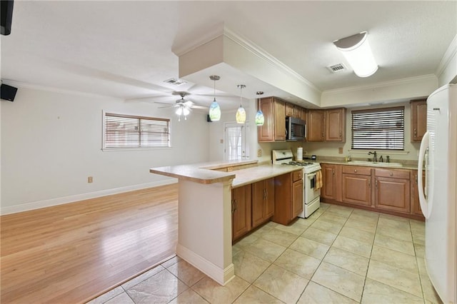 4520 Fairfield St, Metairie, LA 70006 - kitchen featuring white appliances, a peninsula, light countertops, brown cabinetry, and a ceiling fan