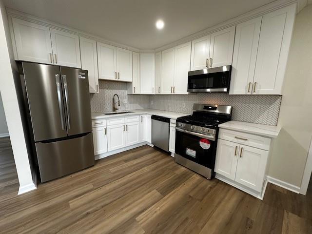 1018 Marian Ave, Metairie, LA 70001 - kitchen featuring appliances with stainless steel finishes, light countertops, white cabinetry, dark wood-type flooring, and decorative backsplash