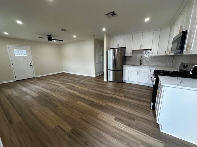 1018 Marian Ave, Metairie, LA 70001 - kitchen with stainless steel appliances, white cabinetry, recessed lighting, tasteful backsplash, and dark wood-style flooring