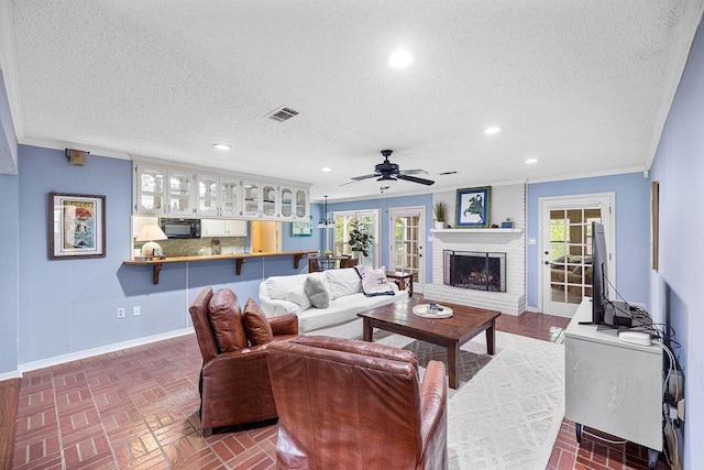 708 W Colorado Ave, Hammond, LA 70401 - living room featuring a ceiling fan, a fireplace, a textured ceiling, brick patterned floors, and plenty of natural light