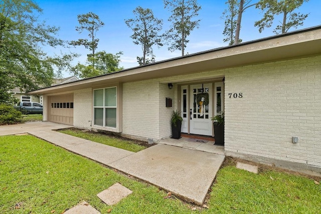 708 W Colorado Ave, Hammond, LA 70401 - doorway to property featuring brick siding, a garage, driveway, and a lawn