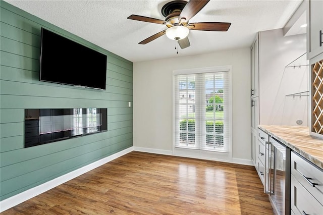811 Franklin Ct, Slidell, LA 70458 - interior space with wine cooler, light wood-style flooring, wooden walls, a ceiling fan, and a textured ceiling