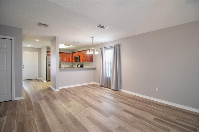 1700 Marseille Dr Unit 16, La Place, LA 70068 - kitchen with appliances with stainless steel finishes, brown cabinetry, light wood-style flooring, light countertops, and a textured ceiling