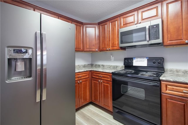 1700 Marseille Dr Unit 16, La Place, LA 70068 - kitchen with stainless steel appliances, brown cabinets, light wood-style flooring, light countertops, and a textured ceiling