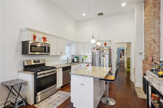 232830 Bienville St, New Orleans, LA 70119 - kitchen featuring appliances with stainless steel finishes, a towering ceiling, a kitchen bar, dark wood-style floors, and a center island