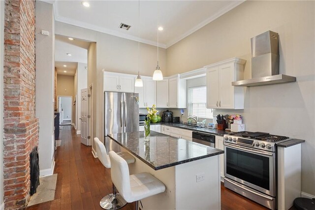 232830 Bienville St, New Orleans, LA 70119 - kitchen featuring stainless steel appliances, wall chimney exhaust hood, white cabinets, crown molding, and a kitchen island