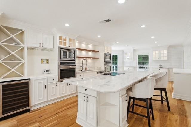 107 Quail St, Slidell, LA 70460 - kitchen with open shelves, wine cooler, stainless steel microwave, light wood finished floors, and recessed lighting