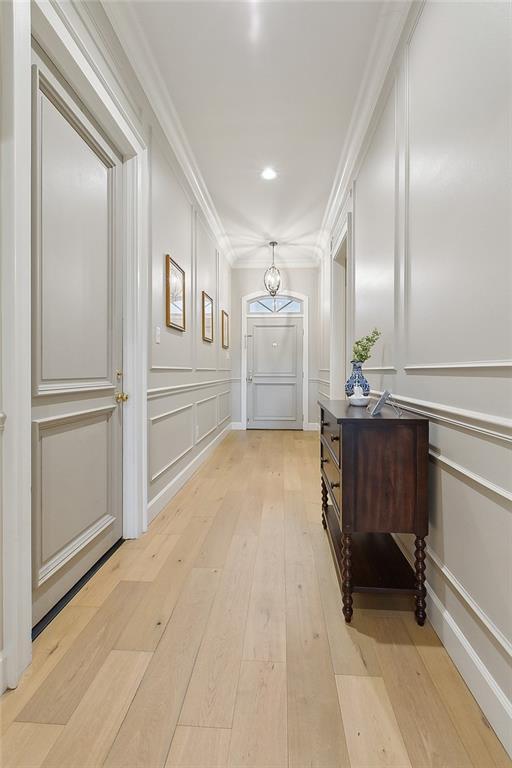 1193 Delta Ln, Covington, LA 70433 - hall featuring a decorative wall, light wood-style flooring, ornamental molding, and a chandelier