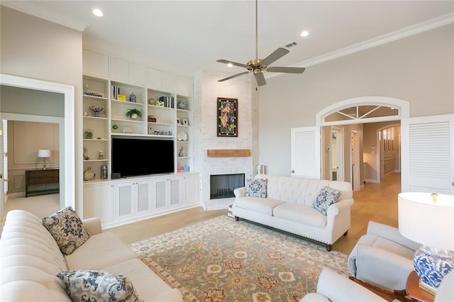 1193 Delta Ln, Covington, LA 70433 - living room featuring light wood-style floors, ceiling fan, ornamental molding, arched walkways, and built in features