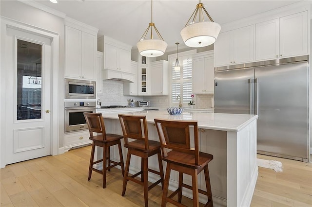 1193 Delta Ln, Covington, LA 70433 - kitchen with built in appliances, light wood finished floors, backsplash, and ornamental molding