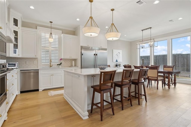1193 Delta Ln, Covington, LA 70433 - kitchen featuring appliances with stainless steel finishes, a kitchen island, decorative backsplash, white cabinetry, and light countertops