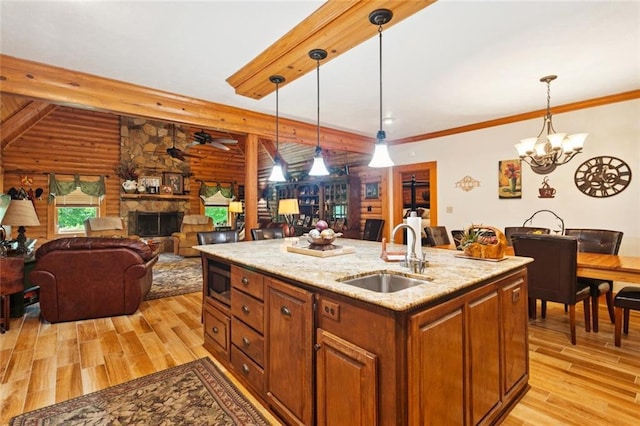 75581 N Hayes Rd, Kentwood, LA 70444 - kitchen with light wood-style floors, a stone fireplace, open floor plan, hanging light fixtures, and beamed ceiling