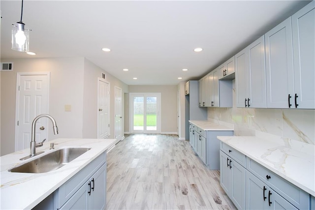 1304 Madewood Rd, La Place, LA 70068 - kitchen featuring light stone countertops, recessed lighting, pendant lighting, light wood-style flooring, and backsplash